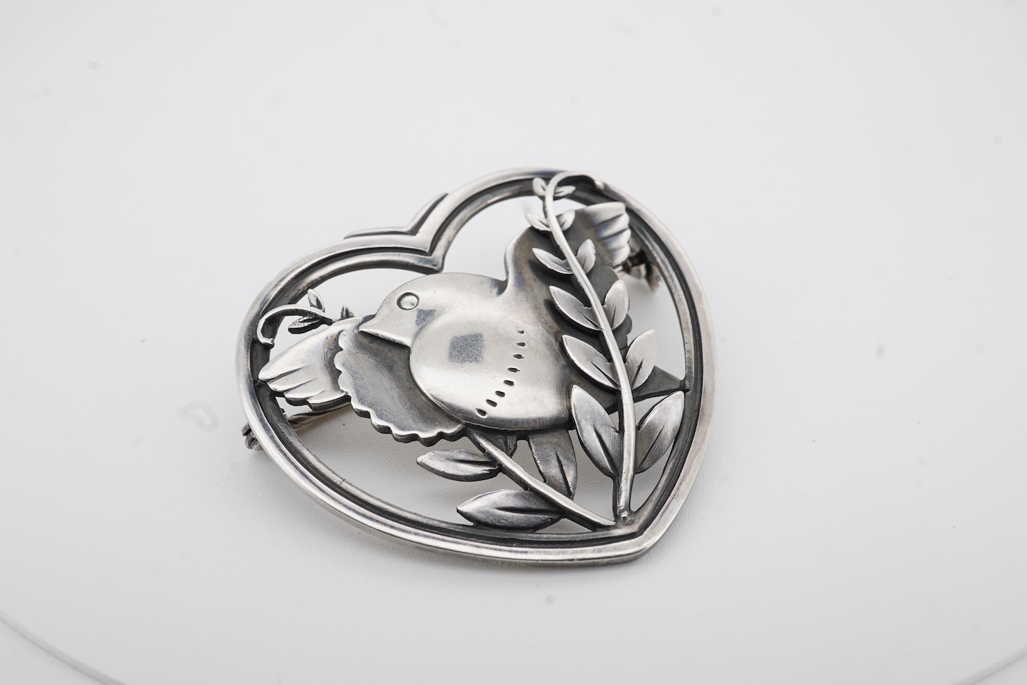 A Georg Jensen sterling heart shaped brooch, designed by Arno Malinowski, depicting a robin with frond, design no. 239, width 40mm.